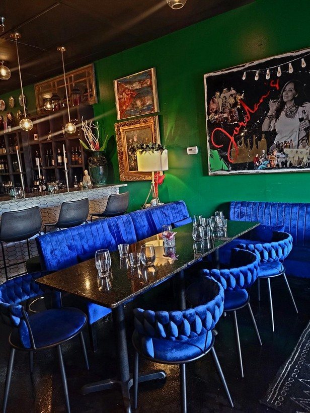 Inside Jordan's Wine Bar — emerald walls, blue seating and glasses on the table