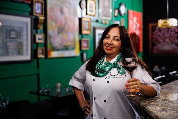 Gloria Jordan in her chef's coat holding a glass of wine