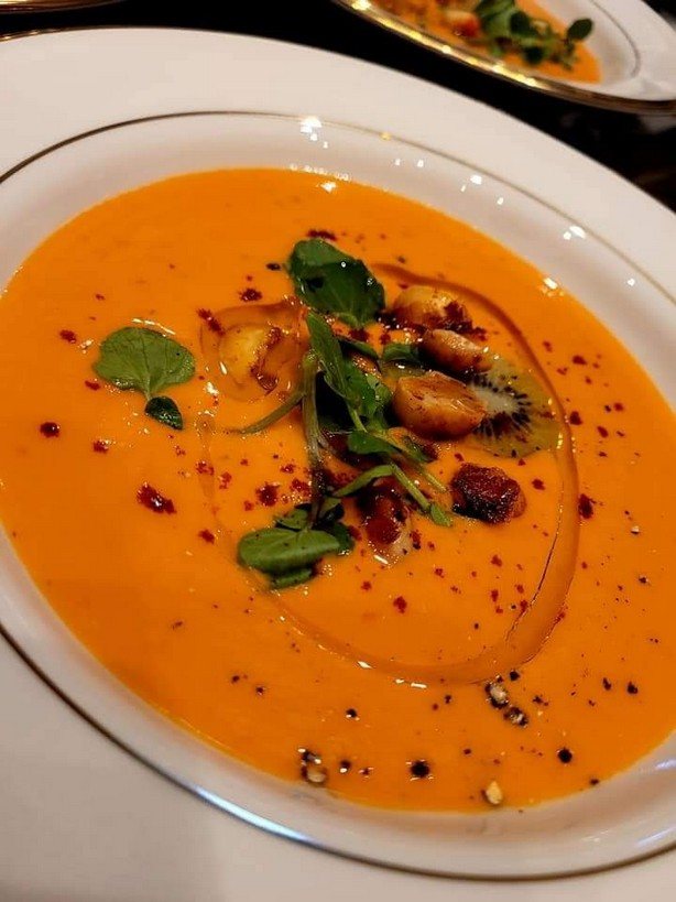 A bowl of smooth soup with greens and a drizzle of oil